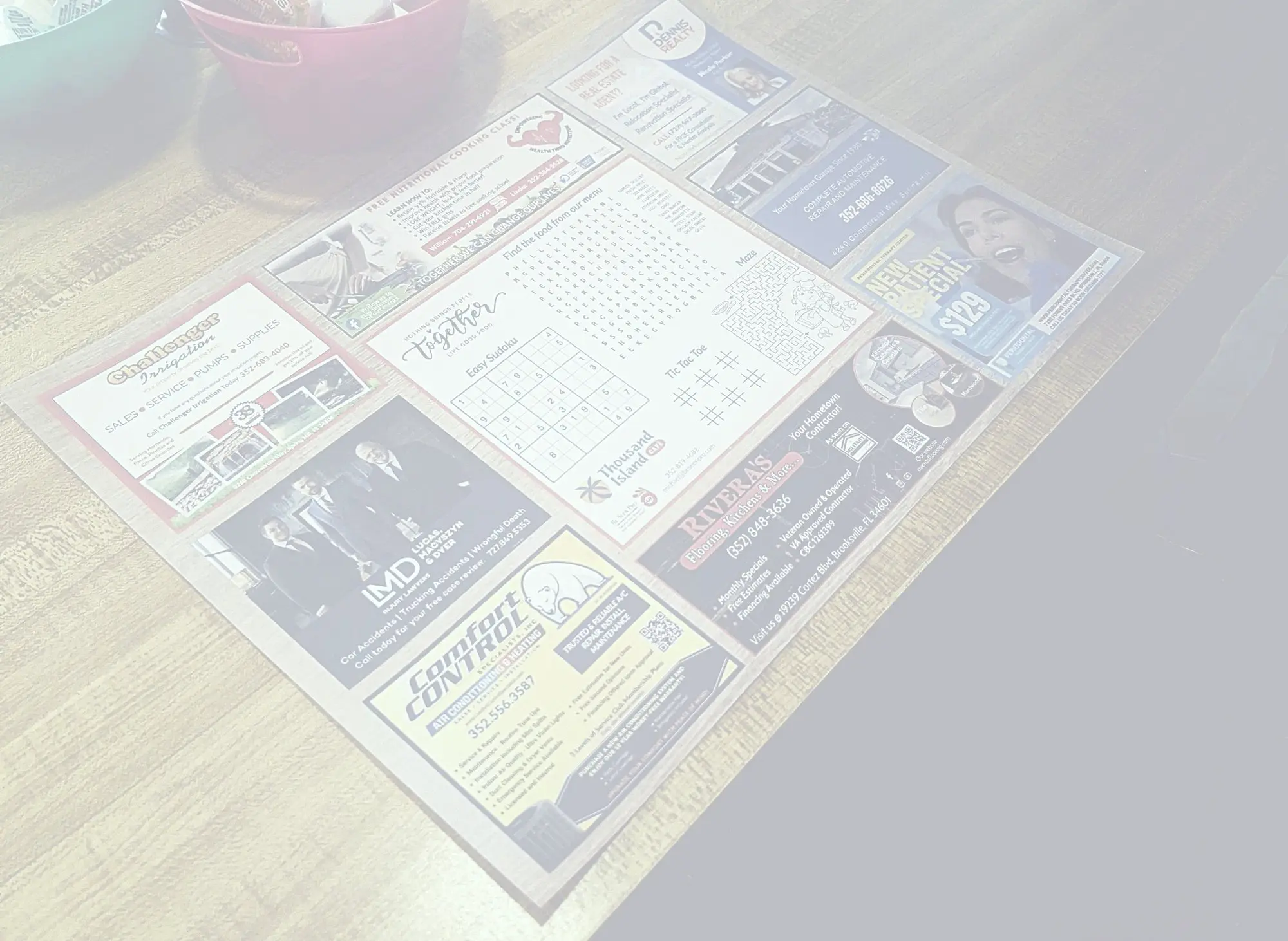 Faded overhead photo of a Thousand Island Cafe placemat with local business ads