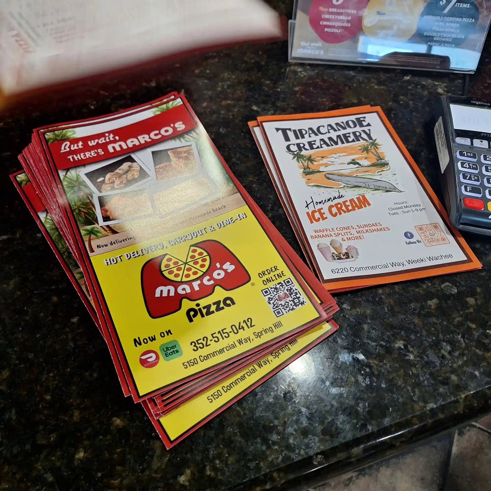 Marco's Pizza menus stacked on a granite restaurant counter