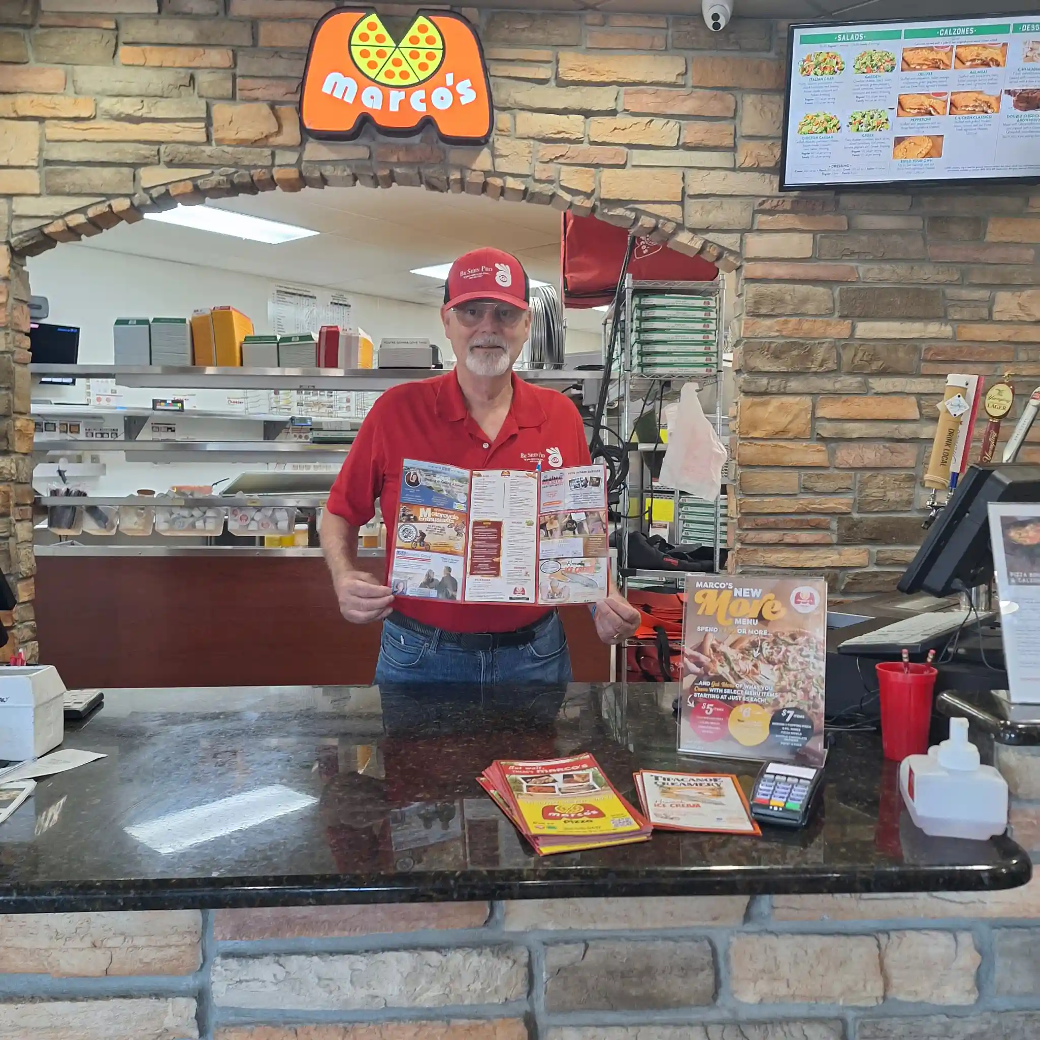 Michael from Be Seen Pro holding a printed menu at Marco's Pizza