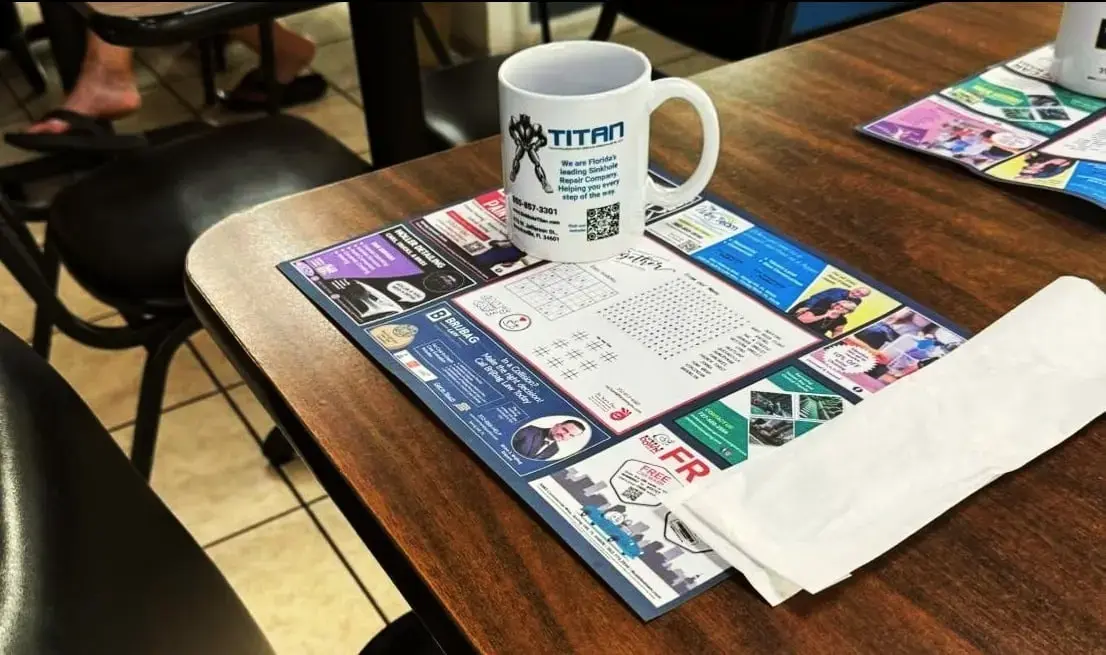 Faded overhead photo of a Thousand Island Cafe placemat with local business ads